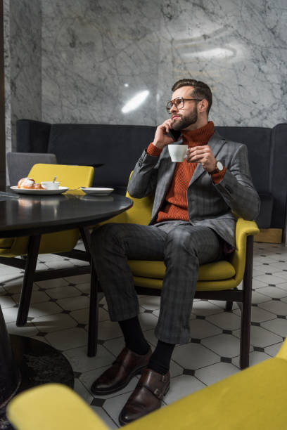 istock handsome man in formal wear talking on smartphone while drinking coffee in restaurant 1082375836