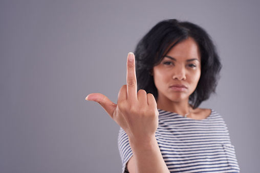 Cropped shot of a young woman holding up her middle finger