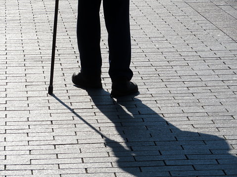 Blind man with blind persons walking stick outdoors at a public park.