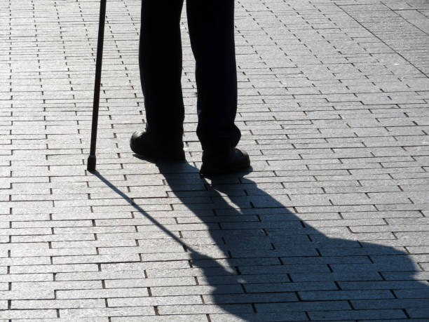 silhueta de homem andando com uma bengala, longa sombra no chão - foot long - fotografias e filmes do acervo