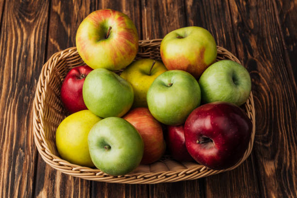 istock wicker basket with ripe multicolored apples on rustic wooden table 1082382394