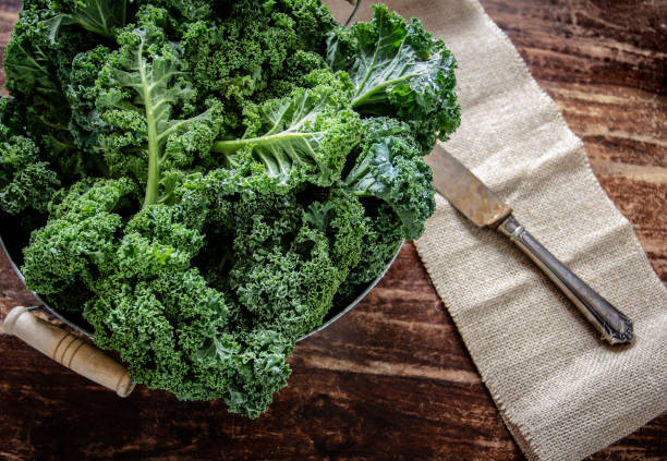 cavolo in cesto e coltello su sfondo in legno vista dall'alto sulle verdure superfood diurne - kale foto e immagini stock