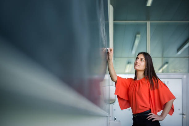 istock Pretty, young college student writing on the chalkboard/blackboard during a math class 1082386148