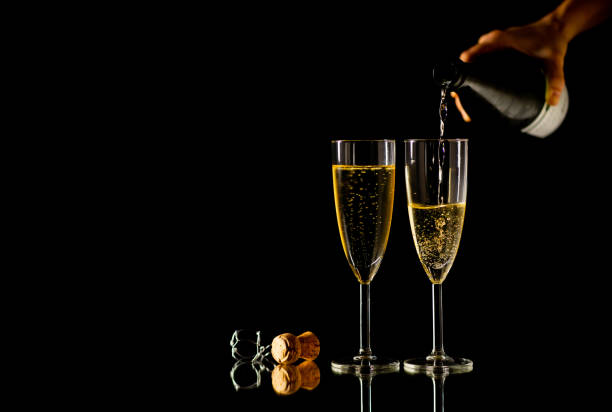 duas taças com champanhe vertendo do frasco pronto para brindar no conceito de celebração no dia dos namorados de natal ano novo e felizes vezes isolaram no fundo preto cópia espaço e studio luz. - cork champagne isolated celebration - fotografias e filmes do acervo