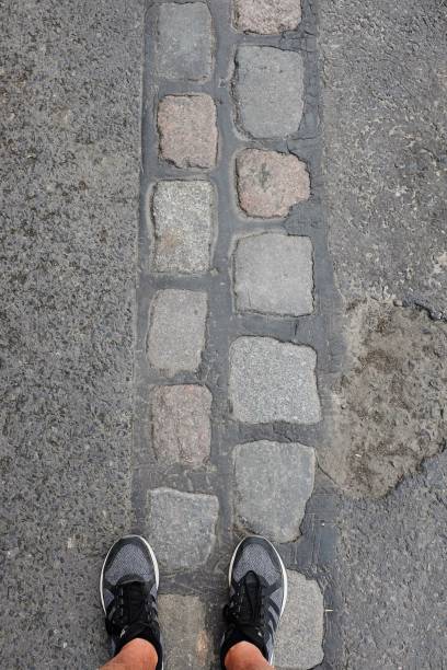 Man leg with with dark sneakers,Black Stone floor texture,Selective focus on boots
