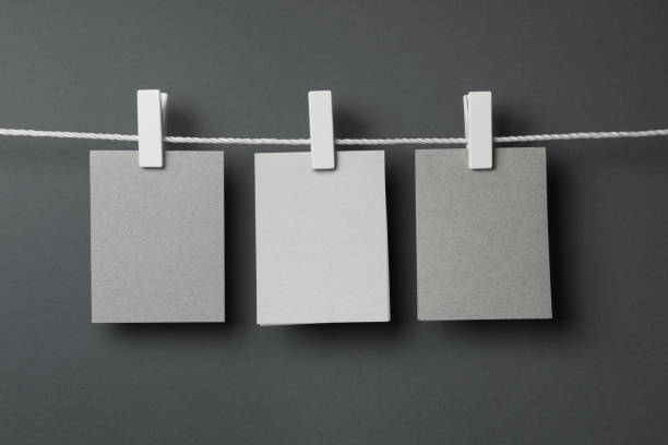 notas de papel en blanco en la cadena sobre fondo gris - adhesive note note pad clothespin reminder fotografías e imágenes de stock