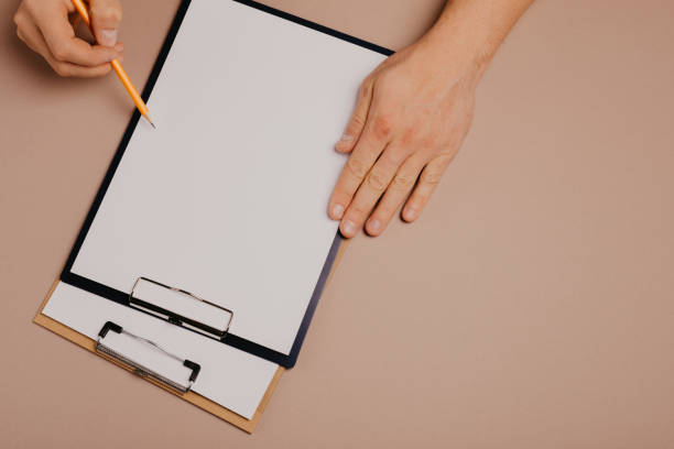 istock man's hands writing on a clip board on a gray background 1082421378
