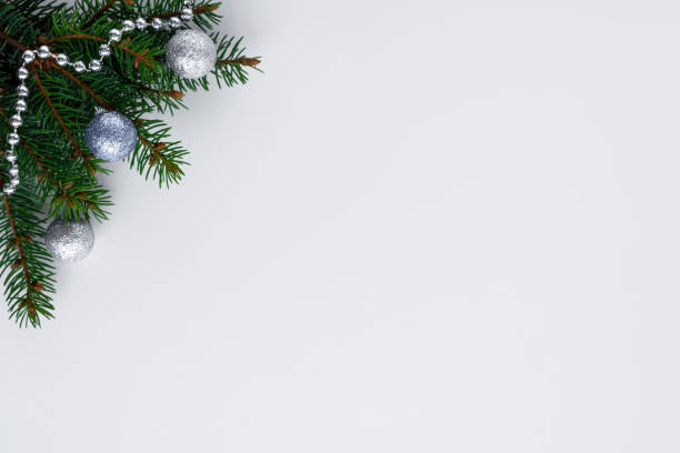 istock Winter holidays festive decorations such as christmas tree branches, silver chain and shiny baubles. White background with blank space for wishes. 1082429622