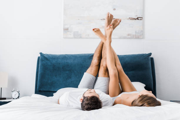 young boyfriend and girlfriend lying with raised legs in morning young boyfriend and girlfriend lying with raised legs in morning feet up stock pictures, royalty-free photos & images