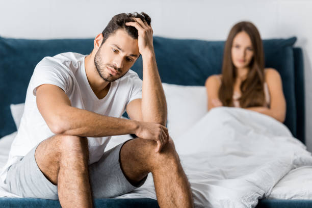 istock selective focus of upset man sitting in bed with hand on head, sexual problems concept 1082434456