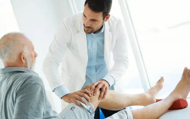 Photo of Senior man having his knee examined by a doctor.