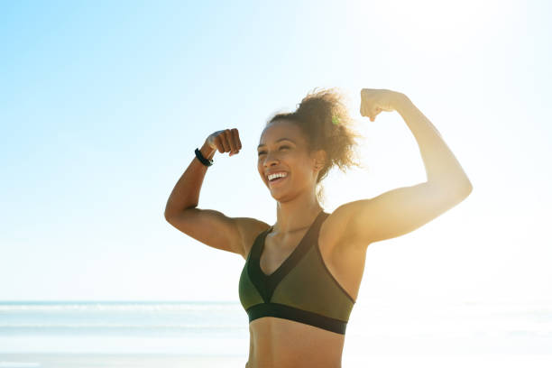 trening zwycięzców - bicep women flexing muscles african descent zdjęcia i obrazy z banku zdjęć