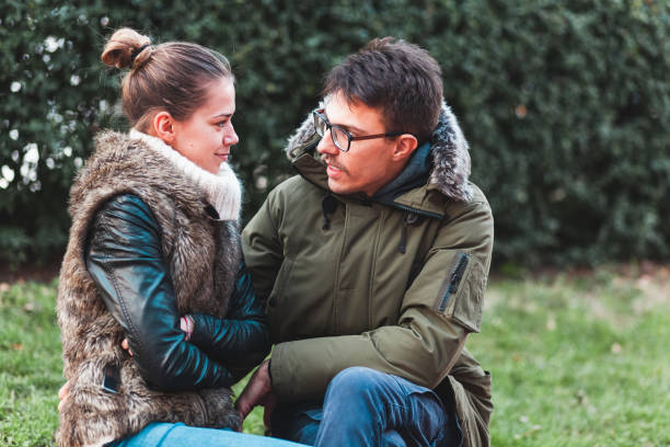 istock Young couple sitting in the park looking at each other 1082437740
