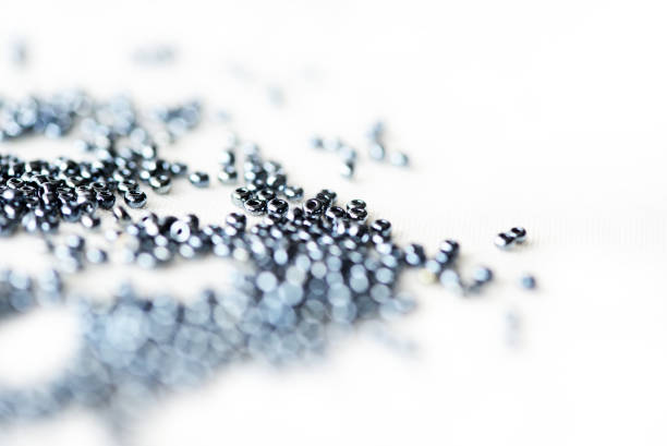 Shining black seed beads scattered on textile background close up