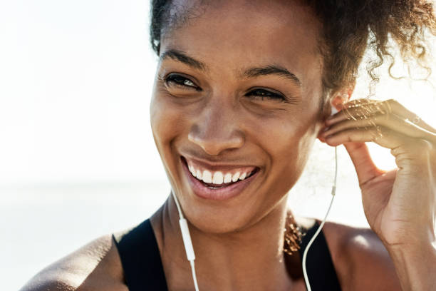 The healthier I am the happier I feel Shot of a fit young woman working out at the beach headphones photos stock pictures, royalty-free photos & images