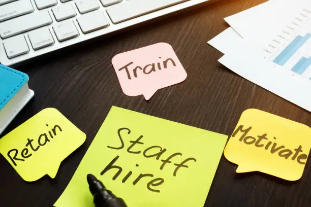 Photo of Staff hire, train, motivate and retain written on a memo sticks.