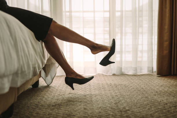 istock Women's legs with black shoes on the bed 1082458440