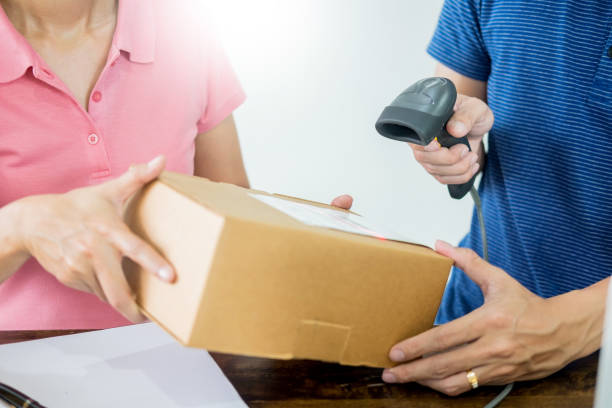istock Close-Up Of Woman Holding Parcel While Delivery Man Scanning Barcode 1082460830