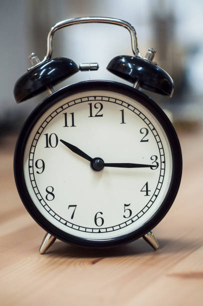 istock vintage alarm clock on wooden table on blurred background 1082460838