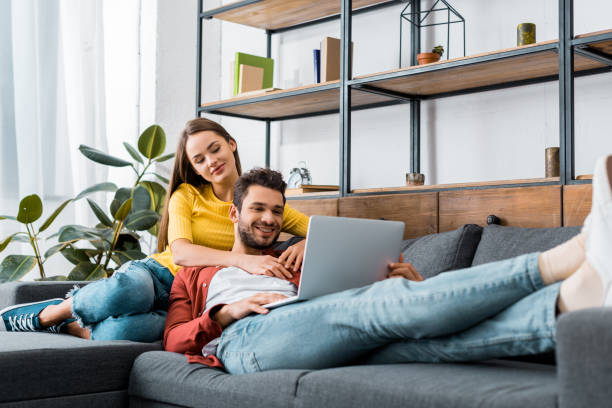 istock young happy couple resting on sofa with laptop 1082470958