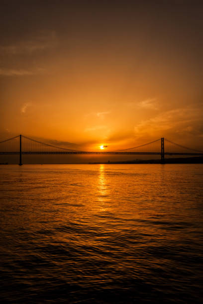 sunset in lisbon with april 25th bridge silhouette in portugal.