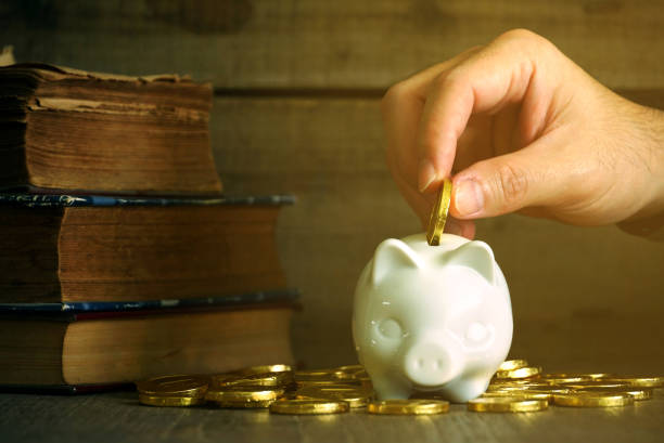 istock Hand fill coin to white piggy save with gold coin on working table 1082477968