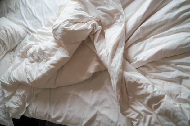cama confortável com messy de linho branco. almofada branca com cobertor na cama unmade. conceito de relaxamento depois de manhã - crumpled sheet - fotografias e filmes do acervo