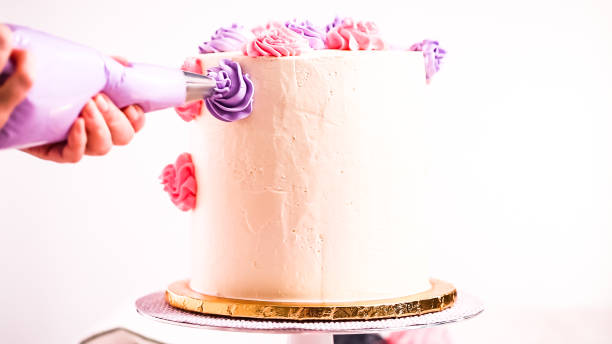 istock Baker piping pastel color buttercream rosettes on a white cake 1082486222