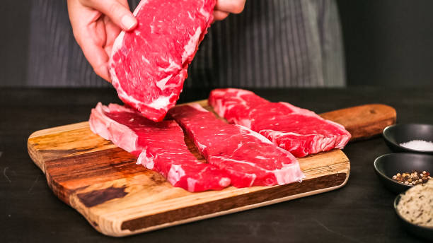 istock Raw New York strip steaks on a wood cutting board. 1082486228