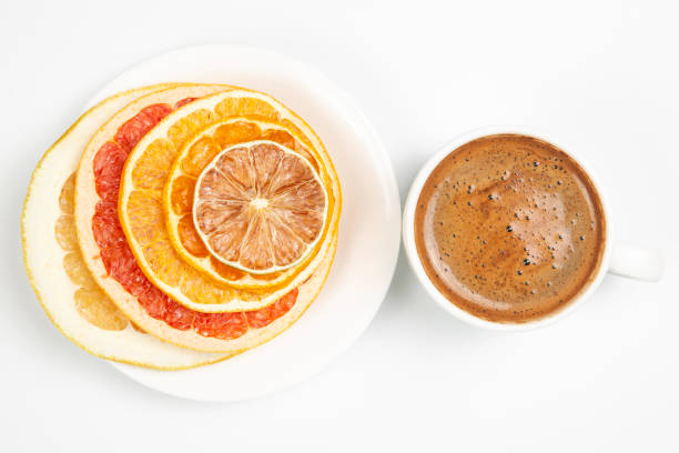 Dried slices of various citrus fruits and black coffee in a white Cup