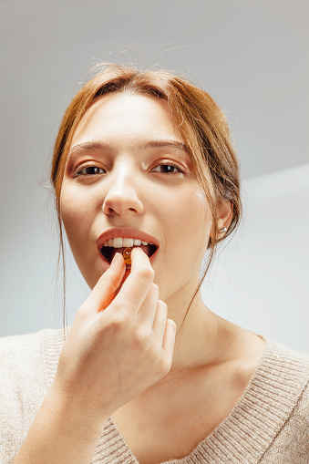 Close Up Of Beautiful Woman Taking Fish Oil Capsule In Mouth