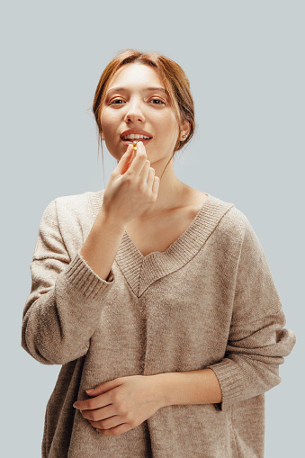 Beautiful Woman Taking Fish Oil Capsule In Mouth