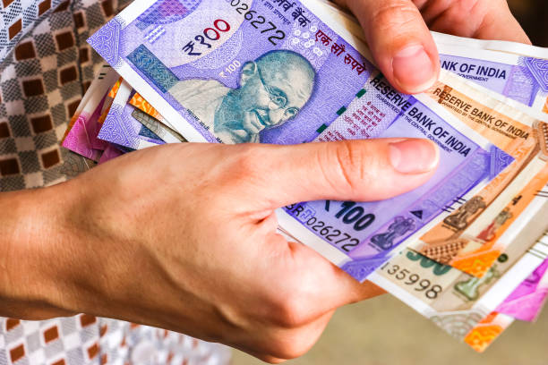 istock Woman's hands with new indian 50, 100, 200, 500, 2000 rupees banknotes. 1082517090