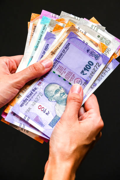 istock Woman's hands with new indian 50, 100, 200, 500, 2000 rupees banknotes. 1082517976