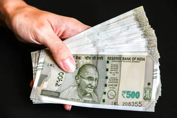 Woman's hands holding brand new indian 500 rupees banknotes.