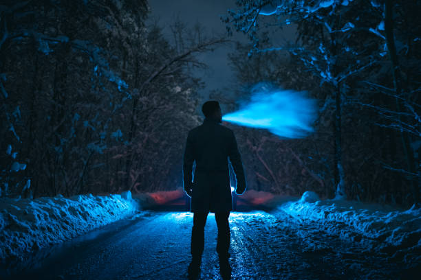 the man smoke on the snowy road in the forest. evening night time - street fog profile imagens e fotografias de stock