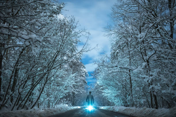 istock The man stand on a snowy road on a bright light background. evening night time 1082549854