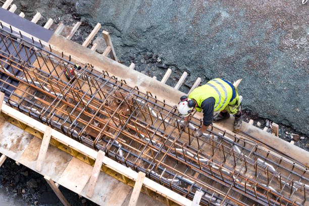 vista dall'alto di un operaio costruttore che lavora a una costruzione di cemento sotto il ponte di tromso, norvegia - construction bridge below concrete foto e immagini stock