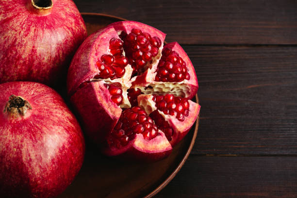 istock Cutted pomegranate in the plate on dark wooden background 1082560294