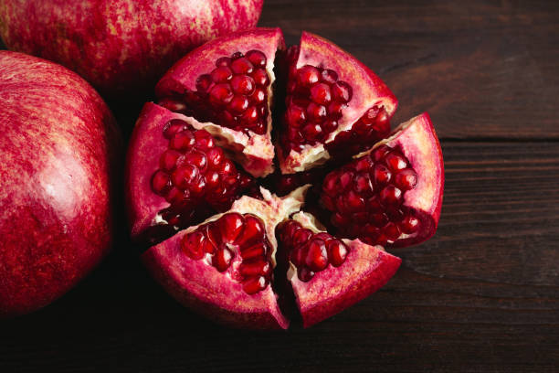 istock Cutted pomegranate on the dark wooden background, top view 1082560392