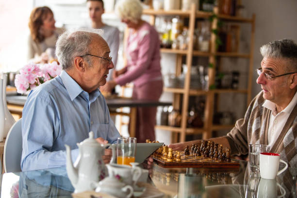 istock Two senior men playing chess at home 1082563994