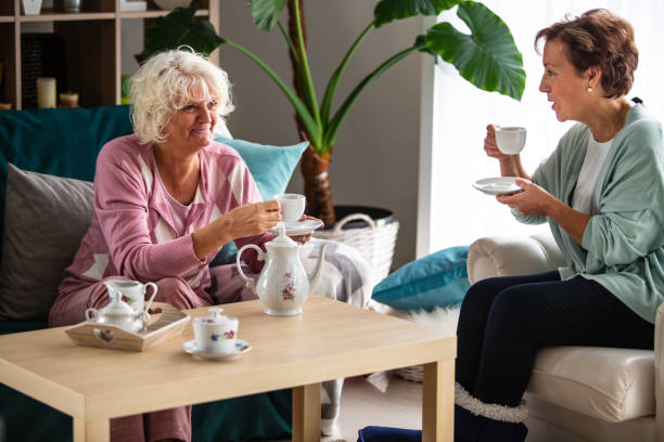 Two senior women drinking tea in the living room
