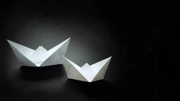 istock Two paper white boats on a dark background. 1082568680