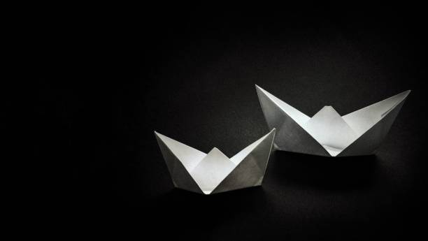 istock Two paper white boats on a dark background. 1082568716