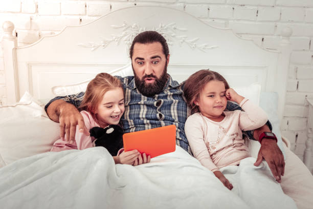 istock Positive nice emotional man hugging his daughters 1082573222
