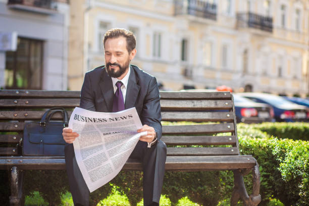 Man Reading Newspaper in sunny park