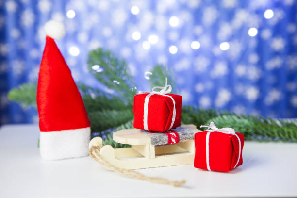 istock Gift boxes on sleigh and Santa hat, on blue background 1082576812