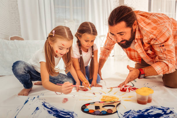 istock Nice bearded man explaining to the girls about painting 1082577482