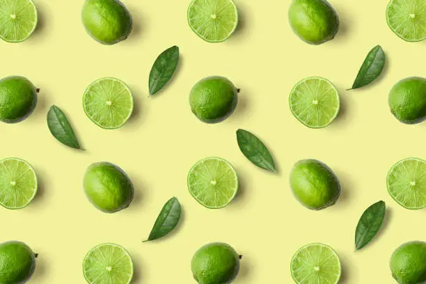 Colorful fruit pattern of limes on yellow background, top view