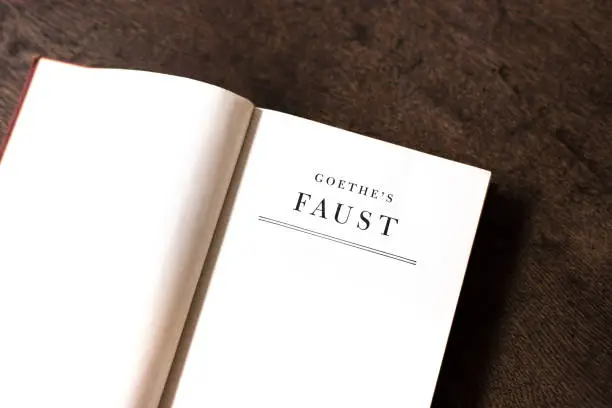 Open Book, Title Page: Goethe's Faust. Brown wood desk background.